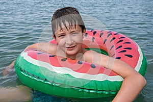 A young playful happy teenage boy relaxing on an inflatable ring ,floaty in the sea during summer vacation