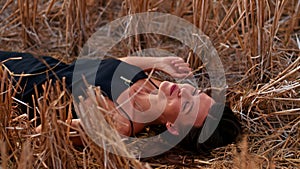 Young playful woman lying on the straw field