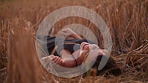 Young playful woman lying on the straw field