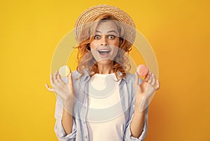 Young pleased woman isolated over yellow background eating macaroons. Girl eat french macarons. photo