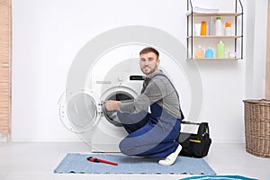 Young plumber fixing washing machine