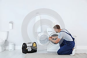 Young plumber fixing washing machine