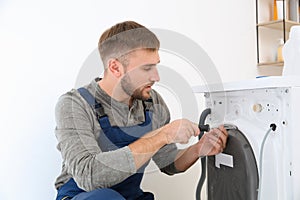 Young plumber fixing washing machine