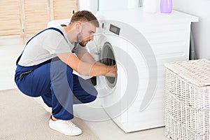 Young plumber fixing washing machine