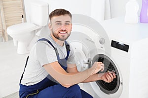 Young plumber fixing washing machine