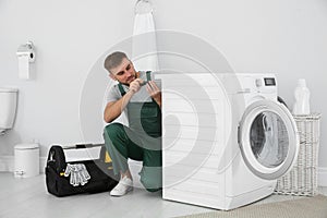 Young plumber fixing washing machine