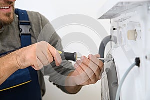 Young plumber fixing washing machine in bathroom