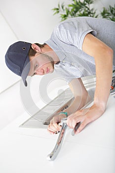 Young plumber installing sink