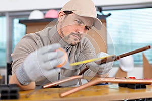 young plumber measuring copper pipe