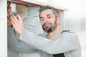 Young plumber working with pipe wrench in kitchen