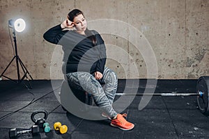 Young plump woman sitting on the barbell