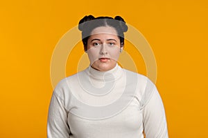 Young plus size girl with double bun hairstyle over yellow background