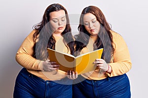 Young plus size twins holding book thinking attitude and sober expression looking self confident