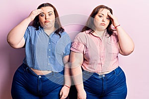 Young plus size twins wearing casual clothes worried and stressed about a problem with hand on forehead, nervous and anxious for