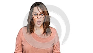 Young plus size woman wearing casual clothes and glasses afraid and shocked with surprise and amazed expression, fear and excited