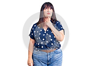 Young plus size woman wearing casual clothes thinking concentrated about doubt with finger on chin and looking up wondering