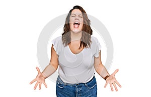 Young plus size woman wearing casual white t shirt angry and mad screaming frustrated and furious, shouting with anger