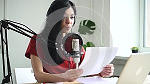 Young podcast presenter woman talk into microphone and read news script Spbd, information concept