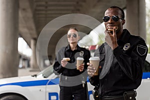 young police officers having coffee break with doughnuts in front of