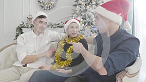 Young positive Caucasian woman talking to twin brothers sitting on both side of her. Three people having fun on