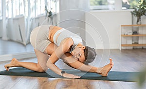 Young positive coach girl in activewear doing stretching exercises during training yoga in sports club