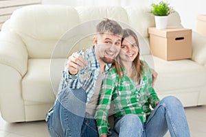 Young positive couple holding keys to a new apartment while standing in their living room. Housewarming and family