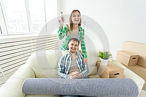 Young funny positive couple holding keys to a new apartment while standing in their living room. Housewarming and family