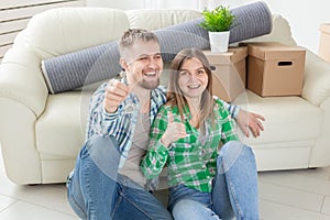 Young positive couple holding keys to a new apartment while standing in their living room. Housewarming and family