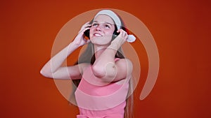 Young positive dancing woman with Christmas cap and headphones