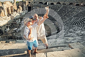 Young positive family take a self photo on the antique amphitheater in Side, Turkey