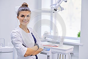 Young positive female dentist doctor with folded arms