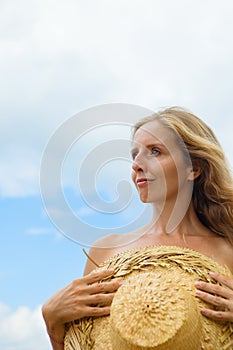 Young positive girl with straw hat relaxing at sea beach