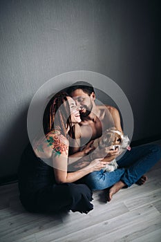 Young positive hipster couple holding a shaggy dog, and smiling