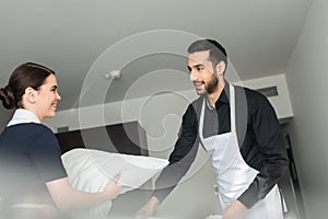 young positive housekeepers changing bedding in