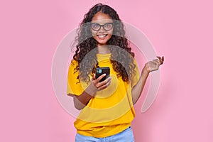 Young positive Indian woman teenager uses mobile phone stands in studio