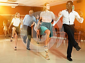 Young positive people dancing twist together at modern dance studio