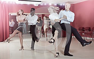 Young positive people practicing vigorous jive movements in dance class photo