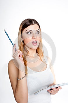 Young positive smiling student girl with notebook and pen planning her daily schedule wearing casual white t-shirt on white. Studi