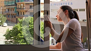 Young positive woman doing chores cleaning window at home