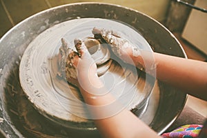 Young potter hands working with clay on pottery wheel