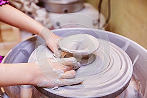 Young potter hands working with clay on pottery wheel