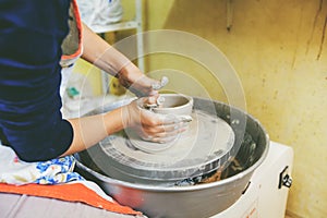 Young potter hands working with clay on pottery wheel