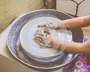 Young potter hands working with clay on pottery wheel