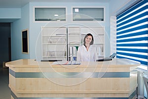 Young practitioner doctor working at the clinic reception desk, she is answering phone calls and scheduling appointments