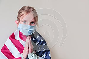 Young praying blonde girl wearing protection mask with American USA flag. Coronavirus, covid-2019 pray for USA.