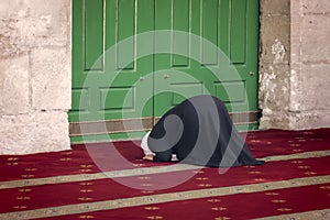 Young praying woman falling on knees against mosque Dome of the Rock in the Muslim quarter of the old city of Jerusalem