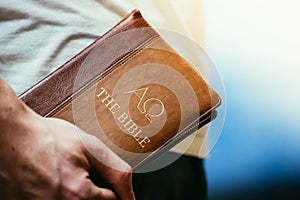 Christian preacher: Young man is holding the bible, praying photo