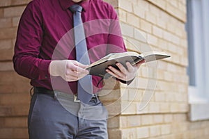 Young Preacher Studies Bible Outside Brick Building