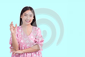 Young preetty Asian beautiful female with black long hair in pink shirt shows present something while isolated on light blue