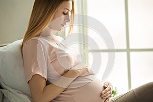 Young preganant woman expecting a baby relaxing on bed indoors